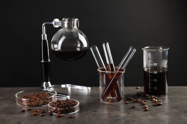 Kahve, fasulye ve bardaklı elektrikli süpürge gri masada.