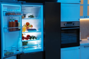 Mutfakta farklı taze gıda ürünleri olan modern buzdolabı.