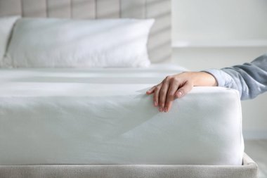 Yatakta yumuşak yatağa dokunan kadın, yakın plan.