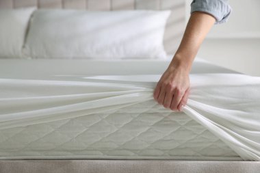 Kadın yatak çarşafını evin içine koyuyor, yakın plan.