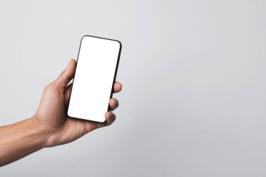 Açık gri arka planda boş ekranlı akıllı telefon tutan adam, yakın plan. Tasarım için model