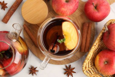 Cam fincanda Aromatik meyve çayı, çaydanlık, beyaz mermer masada elmalar ve baharatlar, düz konum