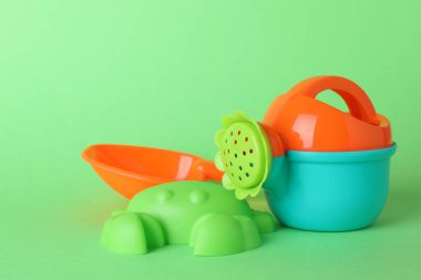 Yeşil arka plandaki çocuklar için plaj oyuncakları. Plastik sulama kutusu, kürek ve küf.