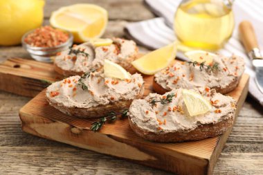 Lezzetli bruschettalar, ezme, limon dilimleri, kekik ve kurutulmuş havuç taneleri ahşap masada, yakın plan.