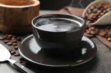 Kahve fincanda, fasulye de gri masada, yakın plan.