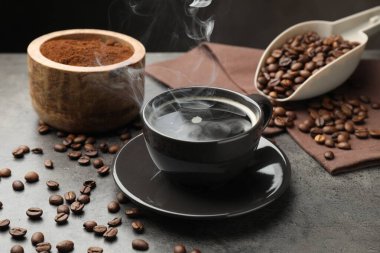 Kahve fincanda, fasulye de gri masada, yakın plan.