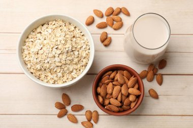 Yulaf gevreği, badem sütü ve açık ahşap masada fındık, düz uzanmış.