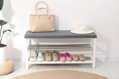 Farklı ayakkabılar, aksesuarlar ve beyaz duvarın yanındaki ev bitkilerinden oluşan ayakkabı deposu.