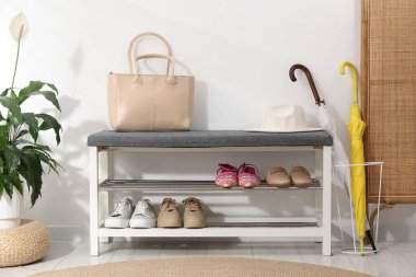 Farklı ayakkabılar, aksesuarlar ve beyaz duvarın yanındaki ev bitkilerinden oluşan ayakkabı deposu.