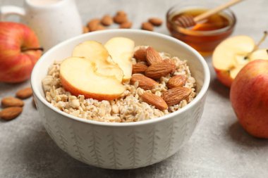 Bademli lezzetli yulaf ezmesi, elmalar ve bal gri masada, yakın plan.