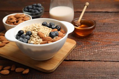 Badem sütü, fındık, bal ve yaban mersinli lezzetli yulaf ezmesi, ahşap masa, yakın plan. Metin için boşluk