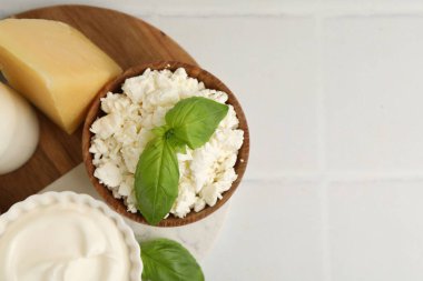 Farklı süt ürünleri ve fesleğen beyaz fayanslı masa, üst manzara. Metin için boşluk