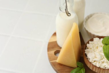 Farklı süt ürünleri ve fesleğen beyaz fayanslı masa, yakın çekim. Metin için boşluk