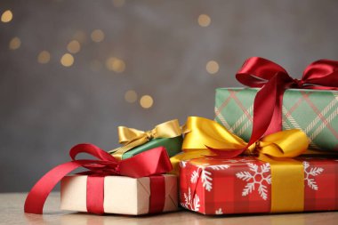 Christmas gift boxes on wooden table against grey background with bokeh lights, closeup. Space for text