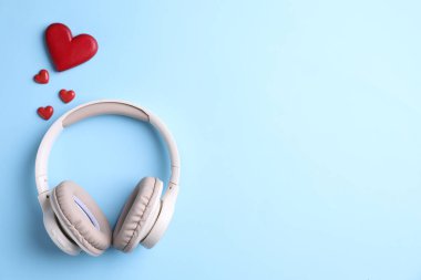 Kulaklık ve kalp figürleri açık mavi arka planda, düz yerde. Metin için boşluk