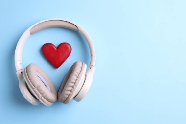 Kulaklık ve kalp figürü açık mavi arka plan, üst manzara. Metin için boşluk