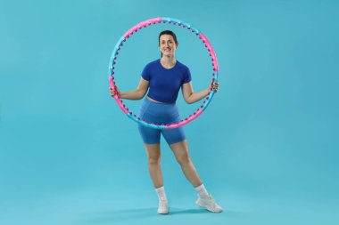 Açık mavi arka planda hula çemberi olan mutlu kadın.