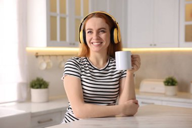 Kahveli kadın mutfakta müzik dinliyor.