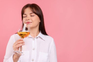 Profesyonel şarap garsonu pembe arka planda beyaz şarap tadıyor, mesaj için yer var.