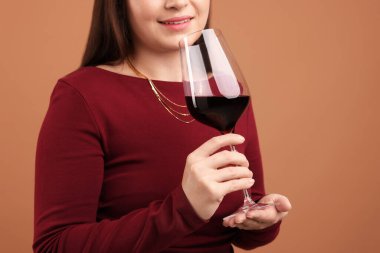 Profesyonel şarap garsonu soluk kahverengi arka planda kırmızı şarap tadıyor.