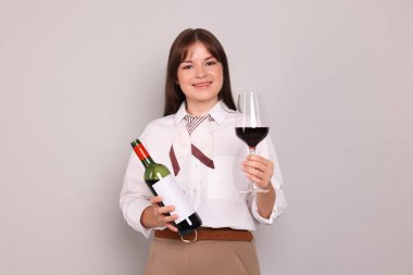 Açık gri arka planda kırmızı şarap ve şişe ile profesyonel şarap garsonu.