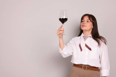 Açık gri arka planda kırmızı şarap kadehi olan profesyonel şarap garsonu.