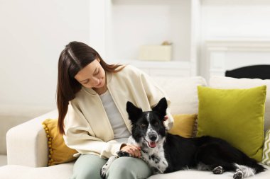 Evdeki kanepesinde Collie köpeği olan bir kadın.
