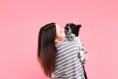 Pembe arka planda sevimli Sınır Köpeği Collie köpeği olan bir kadın.