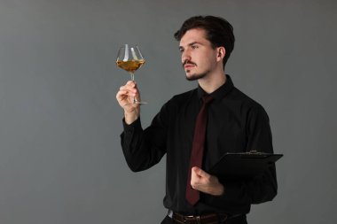 Gri arka planda beyaz şarap ve panosu olan profesyonel şarap garsonu.