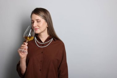 Profesyonel şarap garsonu açık gri arka planda şarap tadıyor. Metin için boşluk