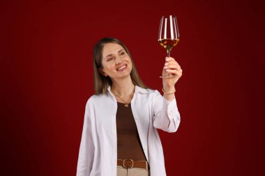 Kırmızı arka planda beyaz şarap kadehi olan profesyonel şarap garsonu.