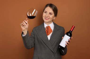 Kahverengi arka planda cam ve şarap şişesi olan profesyonel şarap garsonu.