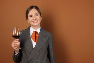 Kahverengi arka planda kırmızı şarap kadehi olan profesyonel şarap garsonu. Metin için boşluk