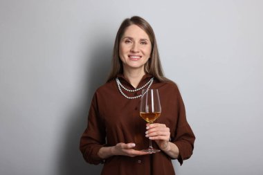 Açık gri arka planda beyaz şarap kadehi olan profesyonel şarap garsonu.