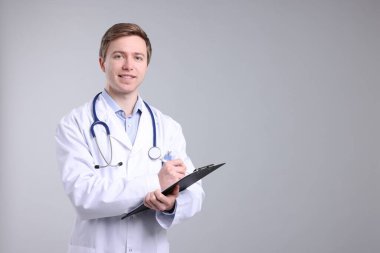 Gri arkaplanda panosu olan tıbbi asistanın portresi, metin için boşluk