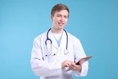 Açık mavi arkaplanda tableti olan bir tıp asistanı portresi