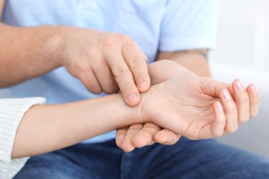 Erkek kadının nabzını kontrol ediyor. Parmakları evde, yakın plan.