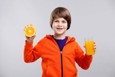 Açık gri arka planda taze portakal suyu ve meyveli çocuk.
