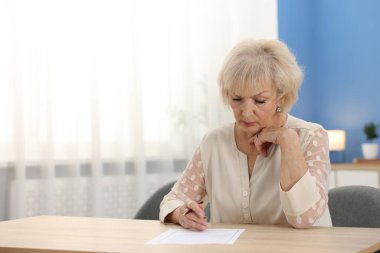Ahşap masada son dilek ve vasiyetnameyi imzalayan üst düzey bir kadın.