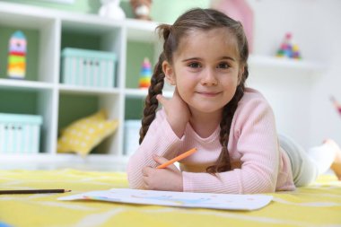 Evde yerde kalemle resim yapan şirin küçük bir kız. Metin için boşluk