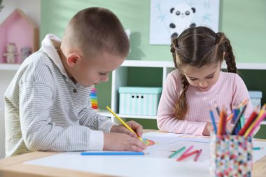 Çocuklar kalemle çizim yapıyorlar.