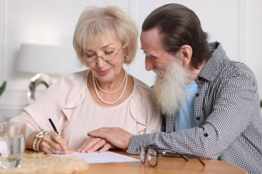 Ahşap masada son arzuları ve vasiyetnameleri imzalayan yaşlı çift.