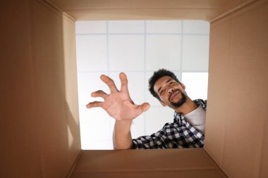 Karton kutuya uzanan adam, paketin içinden görüntüle