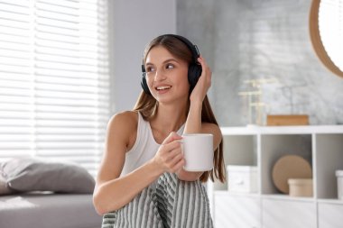 Kahveli güzel bir kadın evde müzik dinliyor.