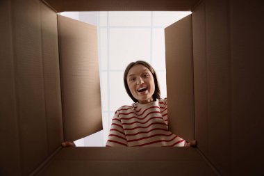 Kadın içerideki karton kutuya bakıyor, içerideki paketi görüyor.