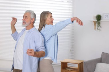 Mutlu yaşlı çift evde dans ediyor.