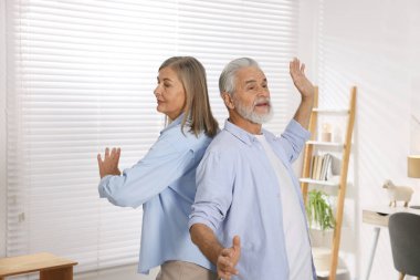 Mutlu yaşlı çift evde dans ediyor.