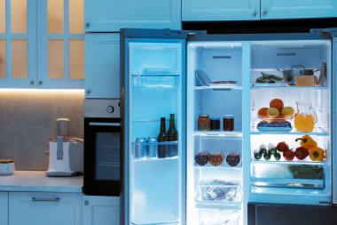 Mutfakta farklı taze gıda ürünleri olan modern buzdolabı.