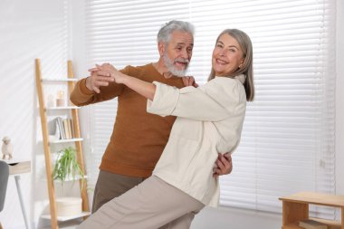 Güzel yaşlı çift evde dans ediyor.