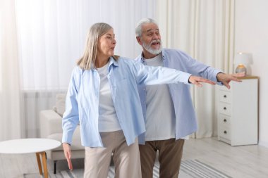 Mutlu yaşlı çift evde dans ediyor.